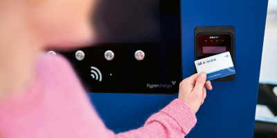 Femme avec pull rose scan sa carte Q8 electric a la borne de recharge