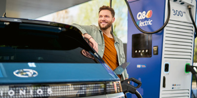 Homme attendant a une borne Q8 electric que sa voiture se recharge