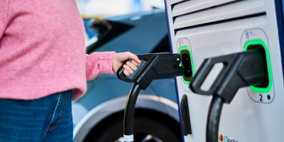 Une femme débranche la borne de recharge Q8 electric